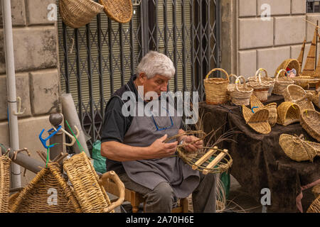 A male basket weaver at a craft market in a hilltop town in Italy working on a basket Stock Photo