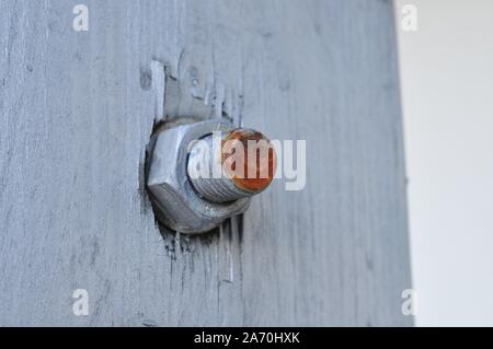 Rusty Red Bolt and Nut on a White Wooden Wall Stock Photo