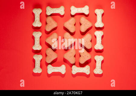 Several multi-coloured dog biscuits arranged in a pattern on a red background nobody in the image Stock Photo