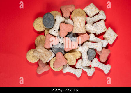 A pile of multi-coloured dog biscuits on a red background nobody in the image Stock Photo