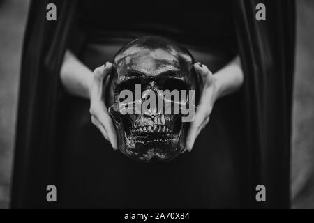 Woman holds skull in hands.Death, spiritual rituals concept, Halloween, horror, scary symbol of dead. Black and white. Stock Photo