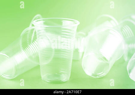White Disposable cups, plates, forks, knives on light green background close-up - Environmental problem concept Stock Photo