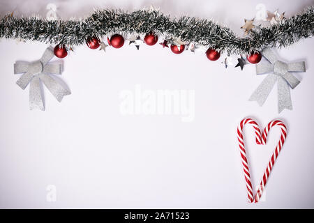 Christmas composition. Garland with red balls, stars, glittery bows and heart made of candy canes on white background. Christmas, winter, new year. Stock Photo