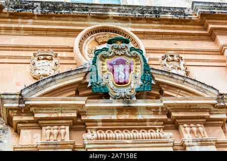 Coloured coat of arms of the archbishop above main entrance to the St Paul's Cathedral in Mdina, Malta. Stock Photo
