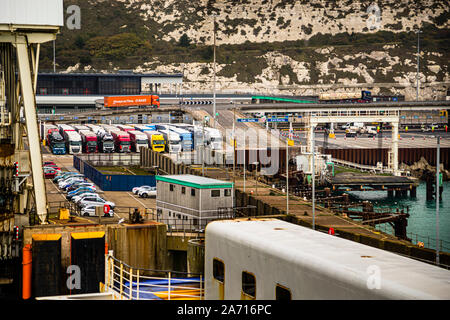 Lorries queue in several lanes for customs clearance at the ferry port of Dover, England. Behind them rise the White Cliffs of Dover, the town's chalk landmark. Little room remains to manoeuvre in the cramped harbour area when traffic comes to a standstill during checks. Stock Photo