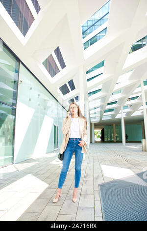 Full length shot of young businesswoman making a call while going to work near modern office building. Stock Photo