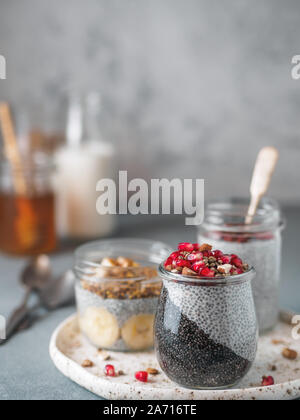 Set of chia pudding in different glass jars on table. Assortment of chia puding with different fruits, nuts,ingredients. Copy space for text. Superfood, detox,healthy overnight breakfast concept Stock Photo