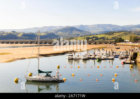 San Vicente de la Barquera, Spain. Views of the Puente de la Maza (Maza Bridge) and the fishing boats in the estuary Stock Photo