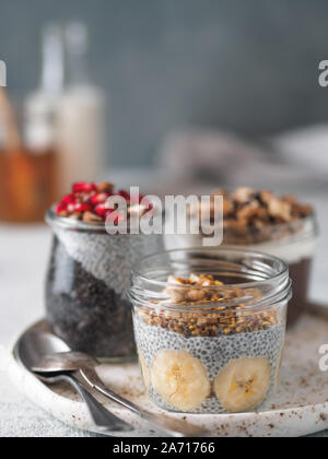 Set of chia pudding in different glass jars on table. Assortment of chia puding with different fruits, nuts,ingredients. Copy space for text. Superfood, detox,healthy overnight breakfast concept Stock Photo