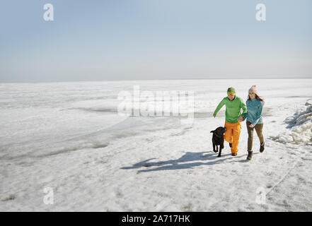 Young adult couple outdoors with dog having fun in winter landscape Stock Photo