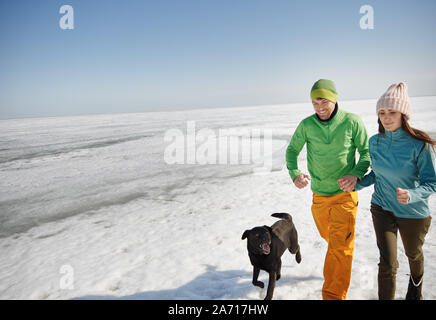 Young adult couple outdoors with dog having fun in winter landscape Stock Photo