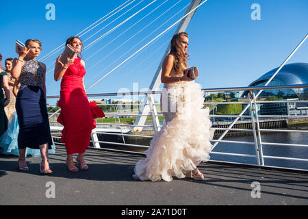 Newcastle, United Kingdom -June 27, 2019: A Bridal and her girlfriends parade in formal dresses and purses on the Millennium Bridge at Newcastle Quays Stock Photo