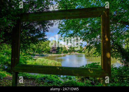 Newcastle, United Kingdom -July 1, 2019: View through large hollow picture frame of pond, trees, ducks and people at Leases Park in Newcastle, England Stock Photo