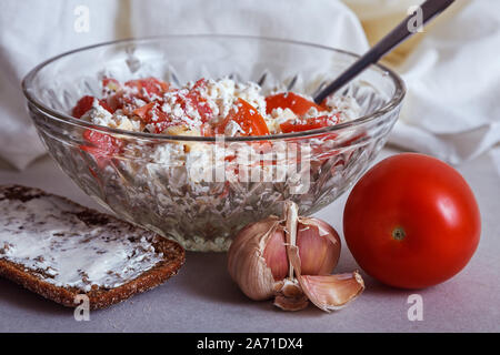 High protein diet salad - low fat cottage cheese, tomato, garlic and herbs in a vintage glass bowl, with a piece of wholegrain rye bread topped with s Stock Photo