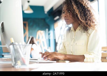 Young african american businesswoman sitting in the office and working on laptop. Stock Photo