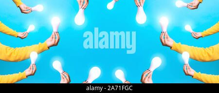 idea solar energy, hands holding light bulbs, illuminated light bulbs over blue background, panoramic image Stock Photo