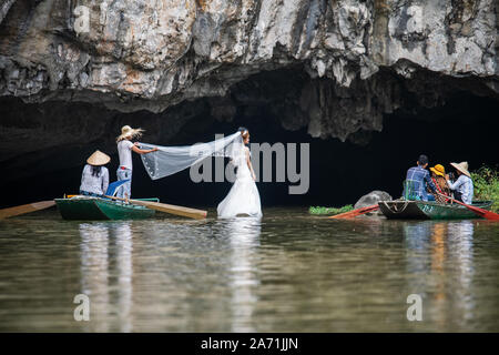 A bride gets her wedding photos taken on a river in Tam Coc, Ninh Binh, Vietnam Stock Photo