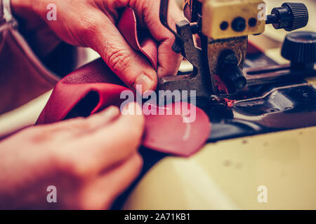 Experienced shoemaker uses a special machine for thinning of the leather, in the handmade footwear industry Stock Photo