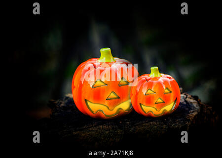 Hallowen pumpkins with shining eyes on a wooden block. Inside has a lighted candle. Stock Photo