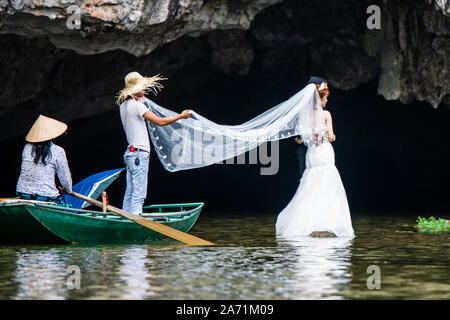 A bride gets her wedding photos taken on a river in Tam Coc, Ninh Binh, Vietnam Stock Photo