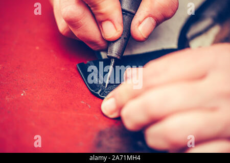 Close up of a shoemaker hands working with leather using crafting tools Stock Photo