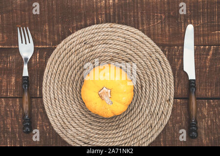 Thanksgiving Day or Halloween place setting with mini pumpkin and cutlery on rustic wooden table, top view with copy space. Stock Photo