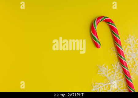 Traditional christmas caramel candy cane and snowflakes on a yellow background. Winter Holiday festive greeting card with copy space for the text Stock Photo