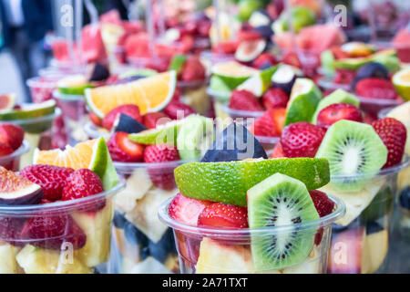 Sliced fruits in plastic cups. Bench on sale. Stock Photo