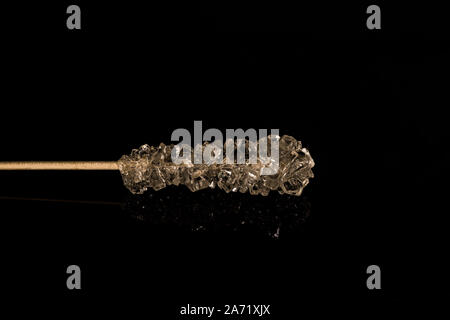 crystallized white sugar on a thin wooden stick on a black background close-up Stock Photo