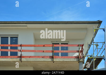 A shell of concrete with provisional balcony and scaffolding against a blue sky Stock Photo
