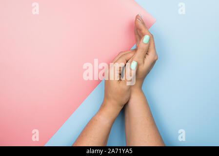 Stylish trendy female blue new manicure. Beautiful young woman's hands on pink and blue background. Stock Photo