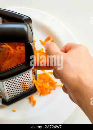 https://l450v.alamy.com/450v/2a724w7/woman-hand-shredding-a-raw-carrot-with-a-metal-vegetable-grater-with-black-plastic-handle-fresh-vegetables-for-healthy-eating-vegetarian-food-2a724w7.jpg