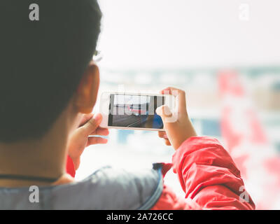 Hand kid person using smartphone or cellphone take a photo the airplan in airport. Airport most popular place for traveler or tourist and walking on w Stock Photo