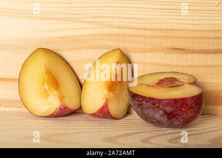Group of one half two slices of fresh red plum on natural wood Stock Photo