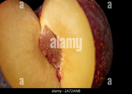 One half of fresh red plum isolated on black glass Stock Photo