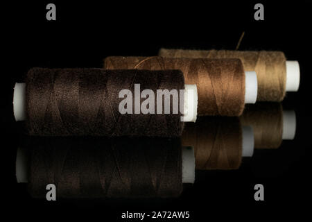 Group of three whole haberdashery item thread spools in row isolated on black glass Stock Photo