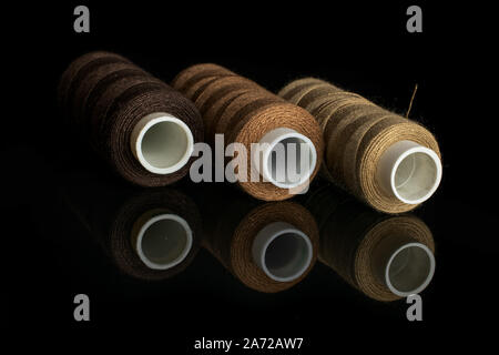 Group of three whole haberdashery item thread spools isolated on black glass Stock Photo