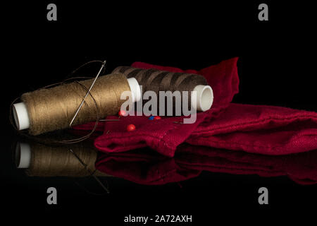 Group of two whole haberdashery item two thread spools needles fabric isolated on black glass Stock Photo