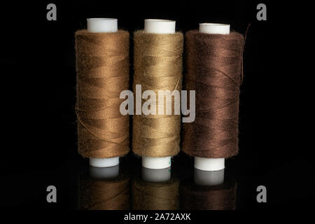 Group of three whole haberdashery item standing thread spools isolated on black glass Stock Photo