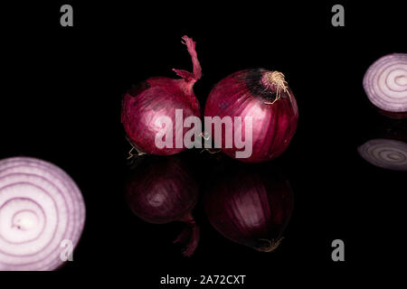 Group of two whole two halves of tasty onion red isolated on black glass Stock Photo