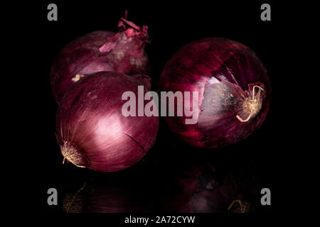 Group of three whole tasty onion red isolated on black glass Stock Photo