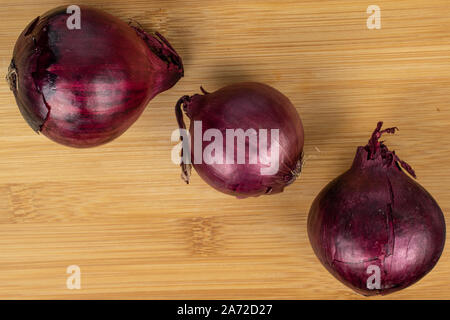 Group of three whole tasty onion red flatlay on light wood Stock Photo