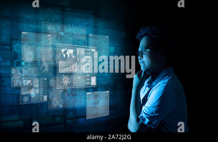 Young business man wearing simple formal attire with eyeglasses putting his hand on chin and thinking while looking at virtual screens analyzing and r Stock Photo