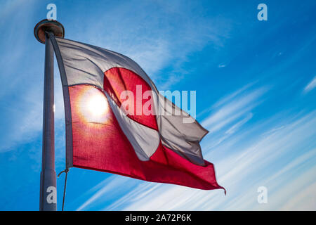 Greenland flag - Greenlandic flag against blue sky. Shot on Greenland on summer day. The National Flag of Greenland.
