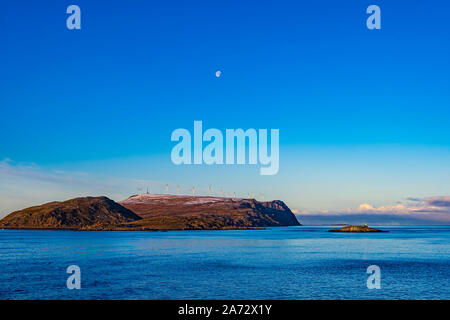 The waning gibbous Moon in the morning sky and in the northwest as we sailed out of the port of Havøysund, Norway. From this latitude of 70° N the Moo Stock Photo