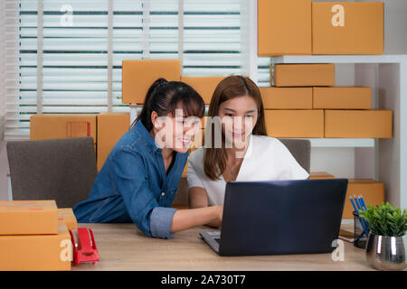 Two Asian teenager owner business woman work sitting on the table for online shopping, checking order  for delivery mail shipping with office equipmen Stock Photo