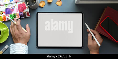 Top view of male artist working on his project on blank screen digital tablet in his creative studio Stock Photo
