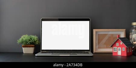 Blank screen laptop computer in dark trendy workplace with office supplies and decorations Stock Photo