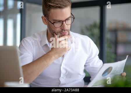 Handsome businessman wearing glasses reading financial news Stock Photo