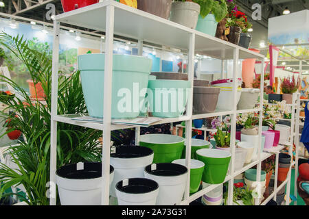 Ceramic multi-colored pots and vases for flowers on white shelves in the market. Stock Photo